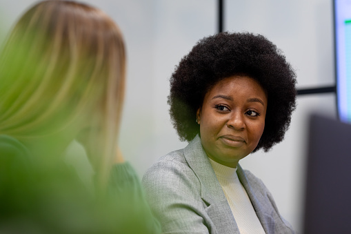 African american businesswoman in discussion at work smiling to business colleague. working person in a modern office