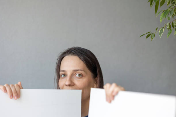 istock Caucasian woman holding white posters, backgrounds, space for text, space for inscription 1314079585