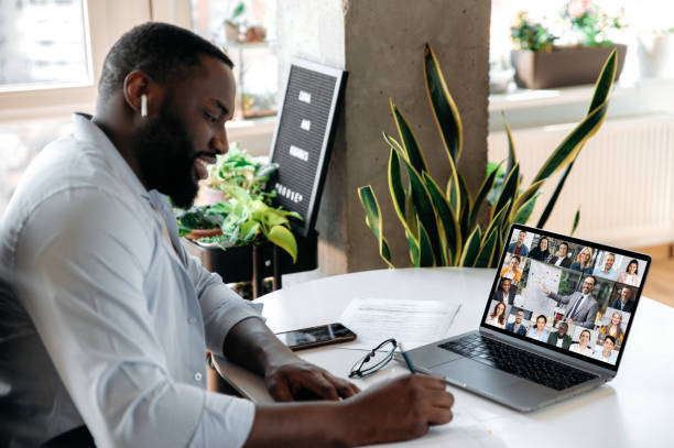 istock Online virtual meeting, e-learning. Focused african american man, student or freelancer, makes notes during online lecture or consultation with business mentor, uses laptop, sits at workplace 1314079641
