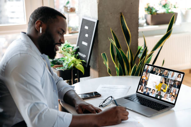 istock Online virtual meeting, e-learning. Focused african american man, student or freelancer, makes notes during online lecture or consultation with business mentor, uses laptop, sits at workplace 1314079646