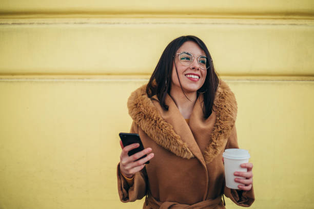 istock Hispanic woman using a smartphone and drinking coffee takeaway 1314080055