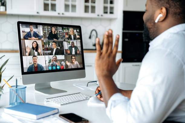 videochiamata, conferenza online. vista a spalla dell'uomo afro-americano sullo schermo del computer con un gruppo multinazionale di uomini d'affari di successo, incontro di lavoro virtuale, concetto di lavoro da casa - conferenza via web foto e immagini stock