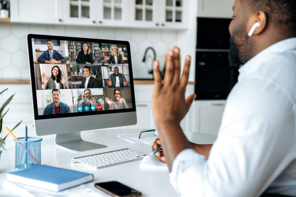 video call, online conference. over shoulder view of african american man at computer screen with multinational group of successful business people, virtual business meeting, work from home concept - home office imagens e fotografias de stock