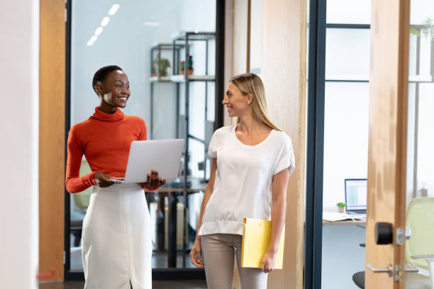 istock Happy diverse female business colleagues walking through corridor holding documents and talking 1314083561