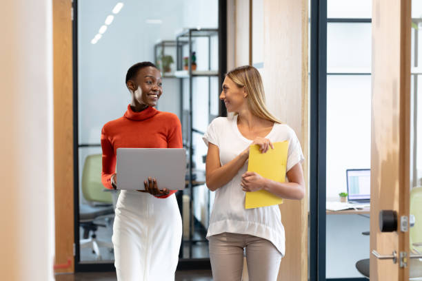 istock Happy diverse female business colleagues walking through corridor holding documents and talking 1314084799