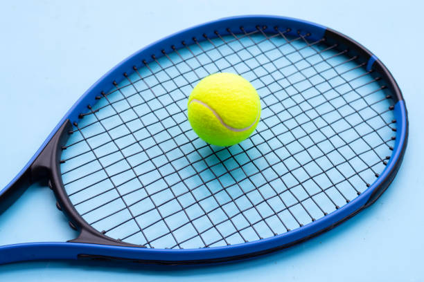 istock Tennis racket with ball on blue background. 1314085283