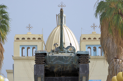 Taulud Island, Massawa, Northern Red Sea Region, Eritrea: Fenkil tank monument on Victory Square - homage to the 2 battles for Massawa in the independence war, 1977 and 1990 - Soviet T-55 main battle tank, known as 'Commander Number 1', the first Ethiopian tank captured by the EPLF, at the battle of Adebzemat in 1977 - in the background the St Mariam Coptic Orthodox Cathedral Church.