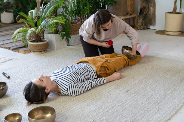 mädchen üben meditation mit tibetischer klangmassage. junge frau entspannt von dersingschalen-therapie - music wellbeing rin gong bowl stock-fotos und bilder