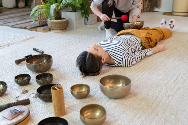 zwei frauen machen tibetische schalen massage zu hause, praxis tibet klangtherapie zusammen für meditation - music wellbeing rin gong bowl stock-fotos und bilder