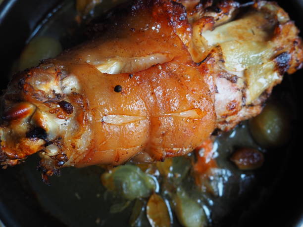 Pork knuckle baked on a baking sheet in the oven with onions, carrots and spices. Delicious restaurant or homemade dish for a festive lunch or dinner. Fatty high-calorie male food. Oven-cooked meat. nudillo de cerdo horneado en una bandeja para hornear en el horno con cebollas, zanahorias y especias. delicioso restaurante o plato casero para un almuerzo o cena festivo. alimentos masculinos grasos con alto contenido calórico. carne cocida al horno