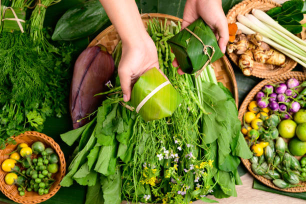 バナナの葉と野菜で包まれた食べ物を手に持つ - banana leaf food thailand thai culture ストックフォトと画像