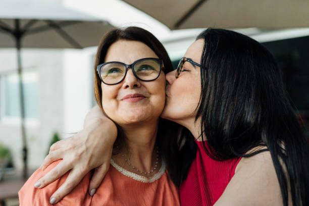 Daughter kissing and hugging her mother Daughter kissing and hugging her mother celebrating the mother's day. daughter stock pictures, royalty-free photos & images