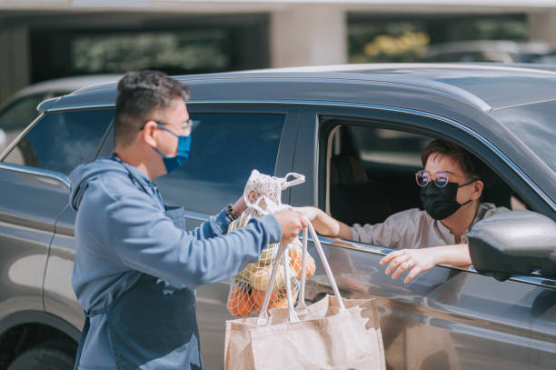 asian chinese mid adult woman Mature woman picking her to go order from her car at a Curbside pickup asian chinese mid adult woman Mature woman picking her to go order from her car at a Curbside pickup curbsidepickup stock pictures, royalty-free photos & images