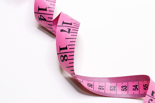 Pink tape measure inches and centimeter isolated in white background
