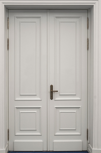 Closed white wooden vintage door on concrete wall. White door