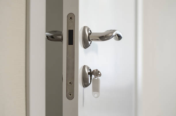 istock Ajar white door with silver handles and a key in the lock 1314119905