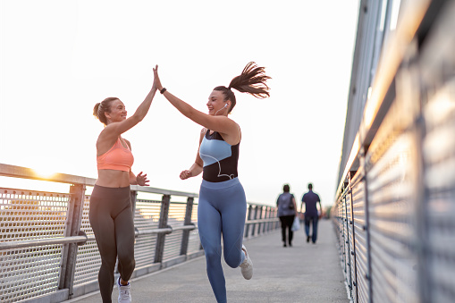 Fitness mujeres amigas en ropa deportiva de cinco para el otro mientras corren juntas photo
