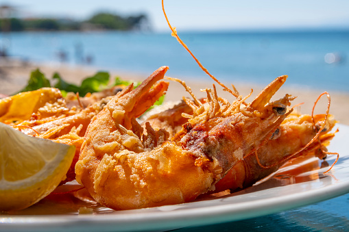 In a hot summer, under sunlight, delicious Greek seafood shrimp on a plate.