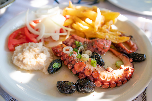 In a hot summer, under sunlight, delicious Greek seafood Octopus on a plate.