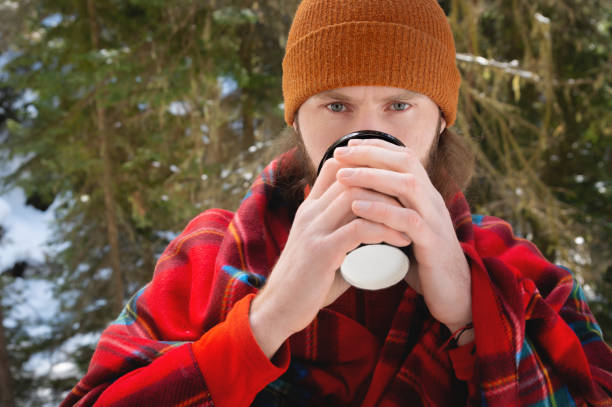 istock bearded man drinking from a paper cup with a blanket on his shoulders 1314134514
