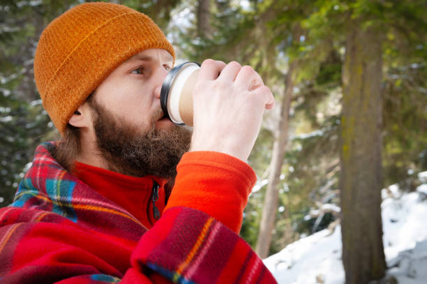 istock bearded man drinking from a paper cup with a blanket on his shoulders 1314134540
