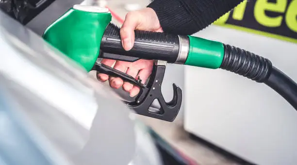 Woman pumping gasoline fuel in car at gas station.