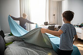 Children making bed in their room before the online lessons