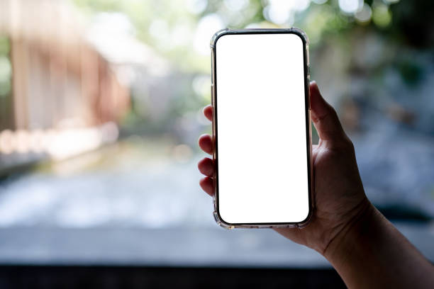 istock Hands holding white mobile phone with blank screen mock up, hotel spa background. 1314140219