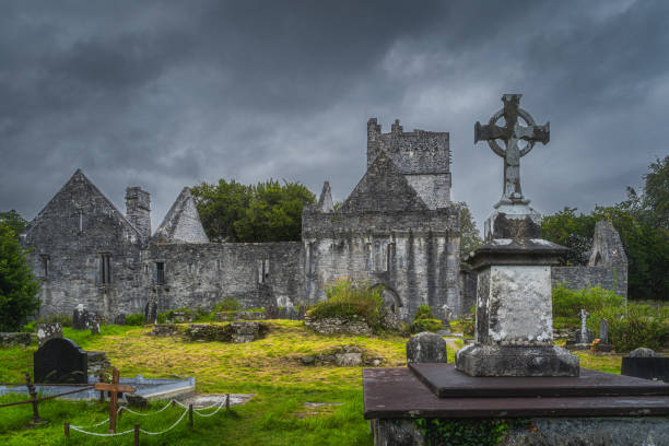 cimetière antique avec la pierre tombale de croix celtique et les ruines de l’abbaye de muckross du 15ème siècle - celtic cross republic of ireland cross shape cross photos et images de collection