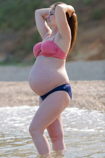 pregnant woman in bikini resting at the sea - ankle deep in water imagens e fotografias de stock