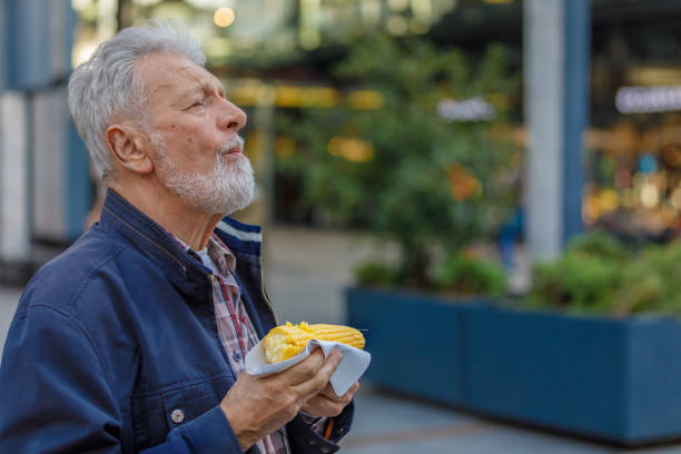 istock An Elderly Man is Walking Through the City and Enjoying Corn Cob. 1314147097
