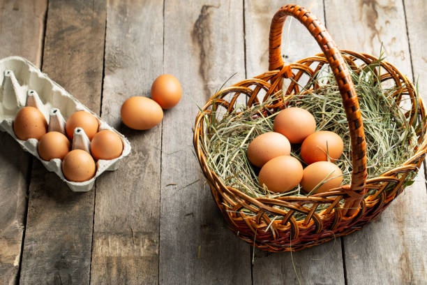 istock Chicken eggs in a hay basket and egg tray, on a wooden table. 1314148060