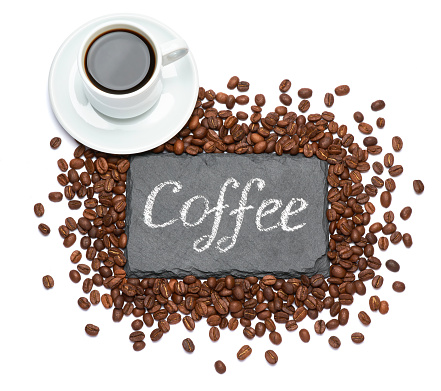 stone serving board with chalk handwritten sign, cup of espresso and coffee beans on white background.