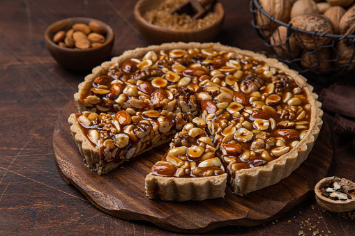 Nut and caramel tart, wooden background, selective focus