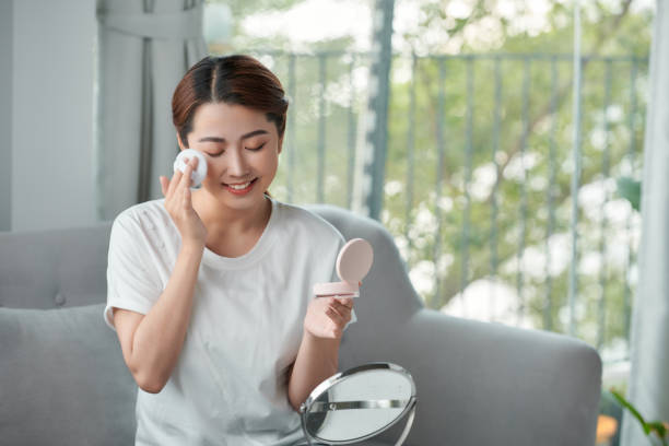 istock Happy young woman applying blush while looking in mirror 1314150948
