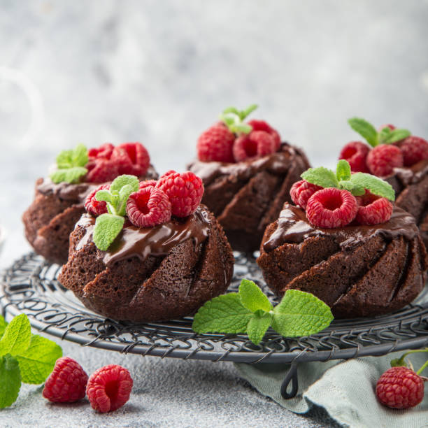 deliciosos muffins de chocolate con cobertura de chocolate y frambuesa fresca - chocolate bundt cake fotografías e imágenes de stock