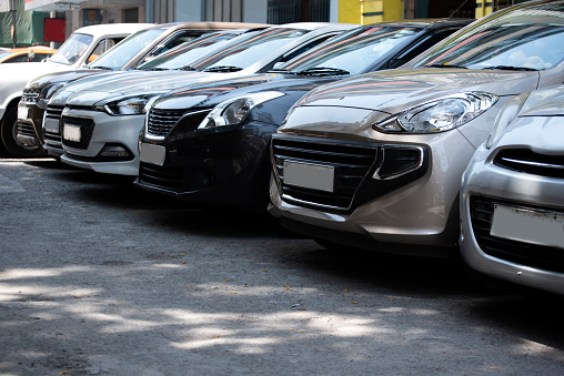 Front view of the of cars parked in a row in road side city Parking lot