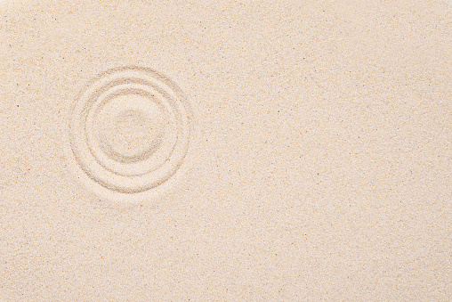 Smooth texture of white sand, top view, layout. Round pattern on sandy background. Concept picture about zen, relaxation, Japanese meditation.
