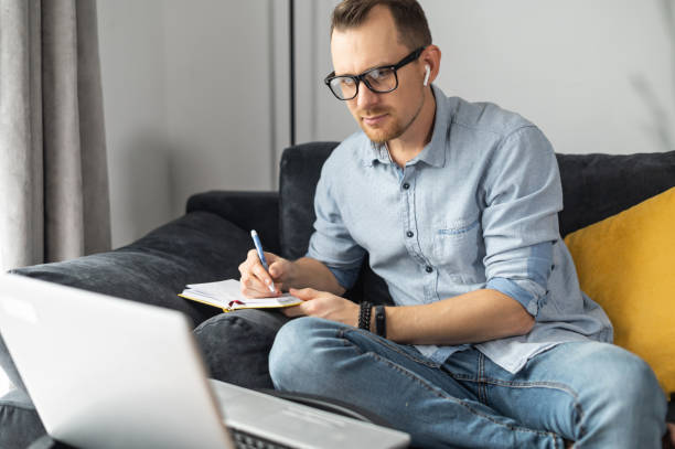 istock A young man with a laptop writing in a notebbook 1314163363
