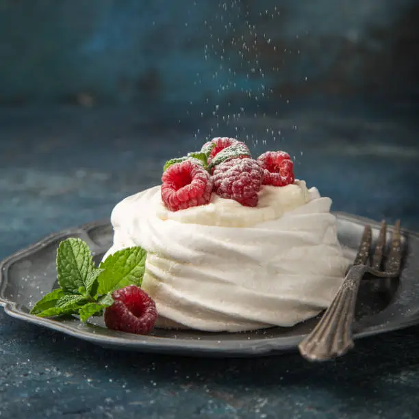 mini pavlova  meringue cakes with whipped cream and fresh raspberry, selective focus, square image