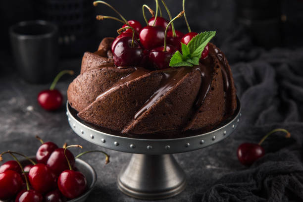 delicioso pastel bundt de chocolate con cereza fresca sobre fondo oscuro - chocolate bundt cake fotografías e imágenes de stock
