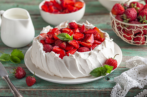 No bake cheesecake with fresh strawberries on top on a white plate on a gray concrete background.