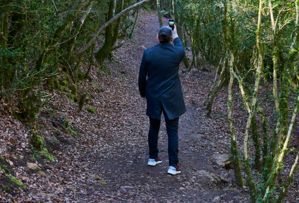 istock Man in coat and mask, photographing the forest with a mobile 1314165654