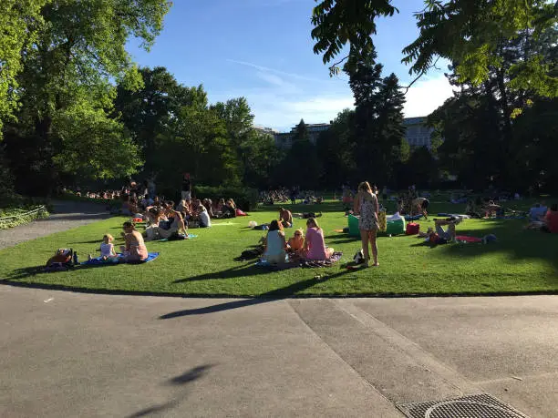 Photo of People sunbathing and picnicking in the Arboretum Zürich, a tranquil lakeside park and botanical garden with picnic and swimming areas amid diverse tree species.