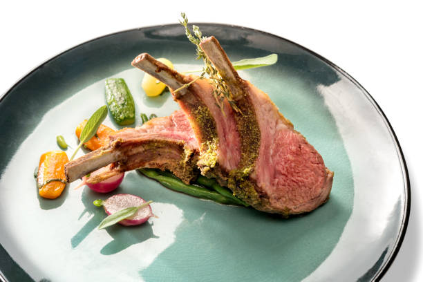 Crusted lamb ribs cutlets Crusted lamb ribs cutlets with bone in green dish with carrot, radishes and courgette, close up, isolated on white rack of lamb stock pictures, royalty-free photos & images