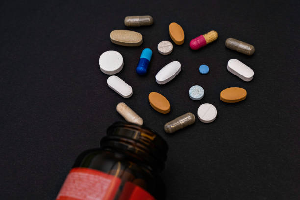 istock Close-up colorful assorted soft capsules pill vitamins in heart shape and jar bottle supplements on black background 1314176647