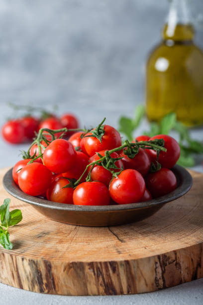 frische kirschtomaten im gericht auf einem holzbrett. - cherry tomato fotos stock-fotos und bilder
