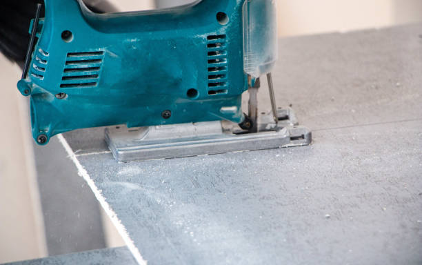 male hands of a construction worker sawing and cutting parts with an electric hand jigsaw from a panel. the process of cutting a building board for interior decoration with an electric jigsaw manos masculinas de los trabajadores de la construcción cortando y cortando piezas con un rompecabezas eléctrico de la mano del panel. el proceso de corte de la placa de construcción para la decoración de interiores con un rompecabezas eléctrico