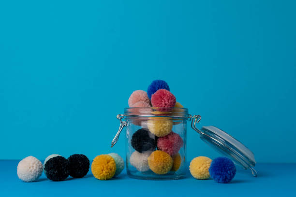Hand made yarn Pompoms for wool crafts in a mason jar stock photo