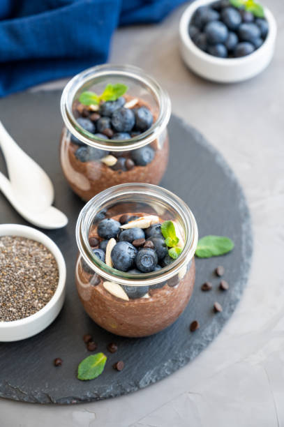 istock Chocolate chia pudding with blueberry, almonds and mint on top in a glass jar on a gray concrete background. Healthy food. Copy space. 1314181527